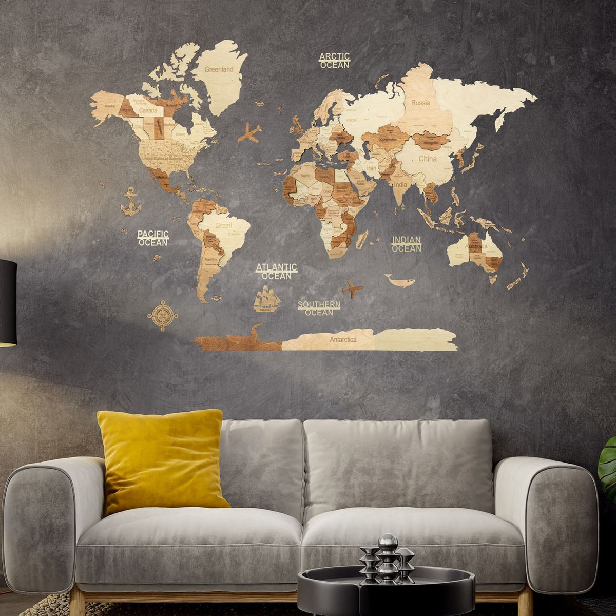 A large world map wall decal with labeled continents and oceans in a rustic wood-grain style, displayed on a dark textured wall above a modern gray sofa with a yellow pillow #Map language_English