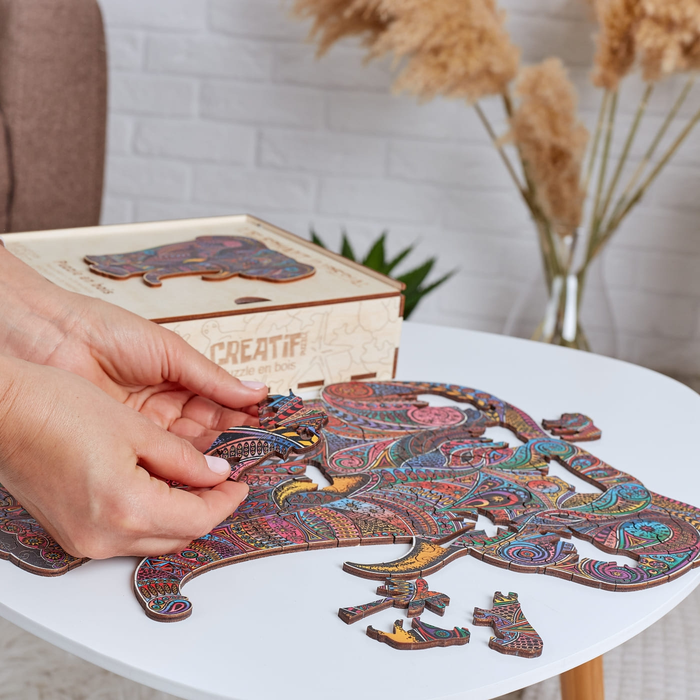 Colorful 3D puzzle of an elephant on a table with a hand placing a piece