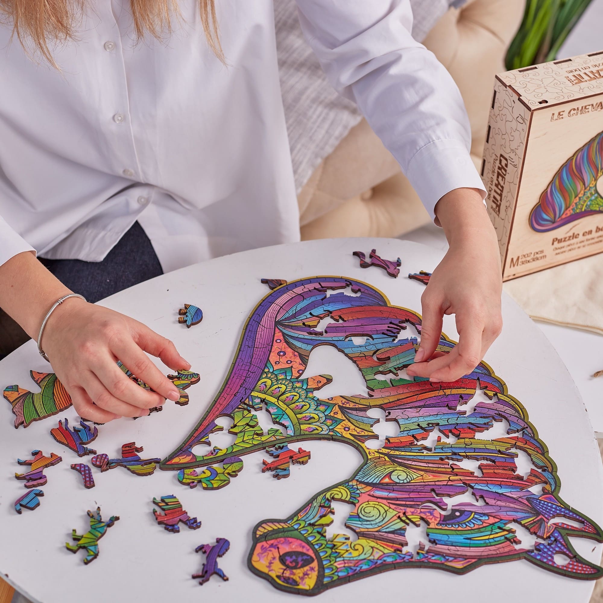 Person assembling a colorful horse-shaped puzzle on a table